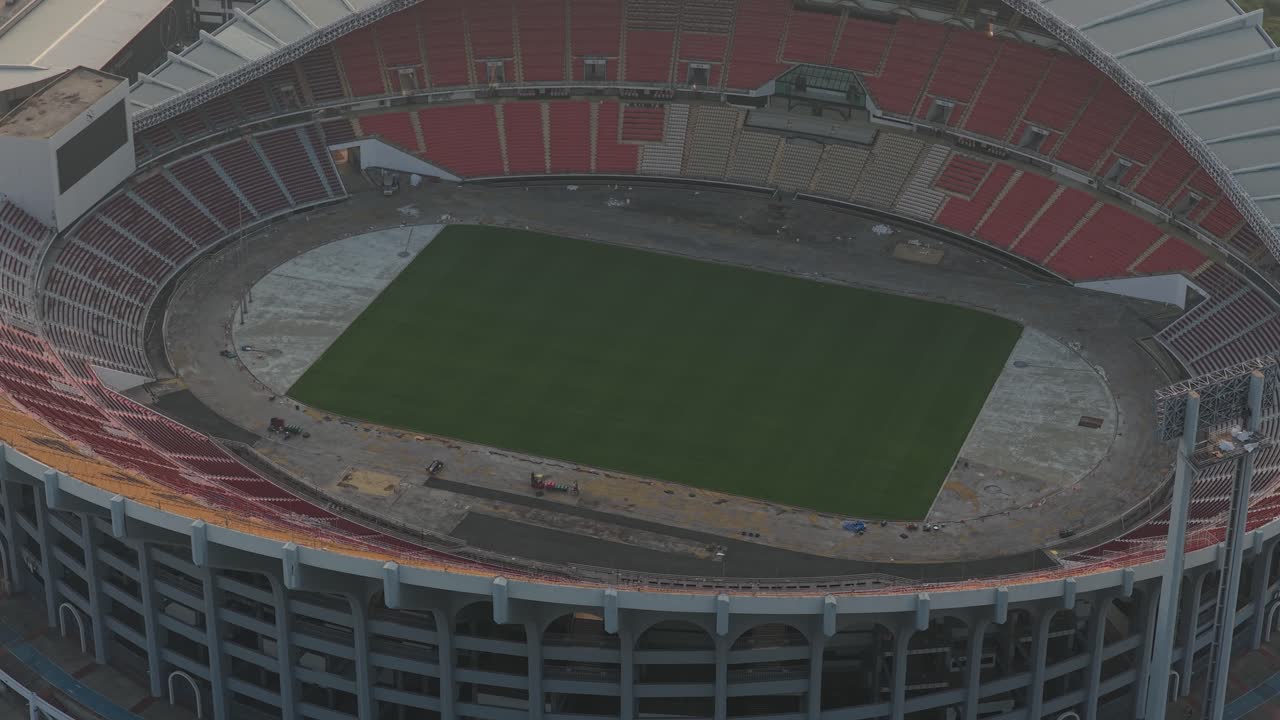 Spettacolare ripresa aerea che orbita lentamente intorno allo stadio nazionale vuoto Rajamangala, rivelandone la grandiosa architettura a Bangkok, Thailandia.