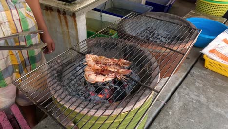 person flipping shrimp on a charcoal grill