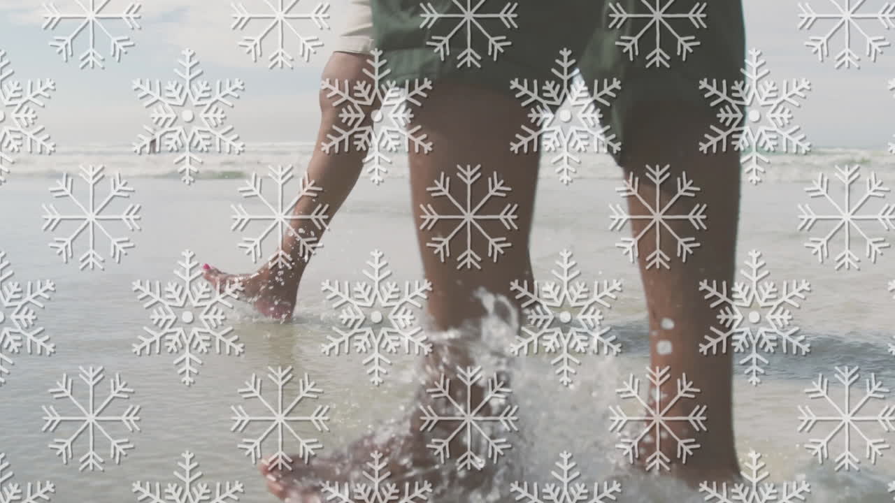 Walking on beach, person with snowflake animation overlaying scene in winter