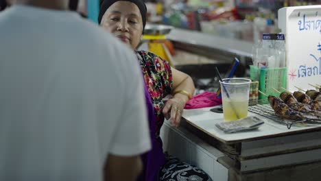 woman selling grilled fish at a market stall