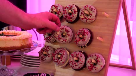 A-board-with-handles-on-which-doughnuts-are-hooked---sweet-colorful-pastries-with-icing-drizzle