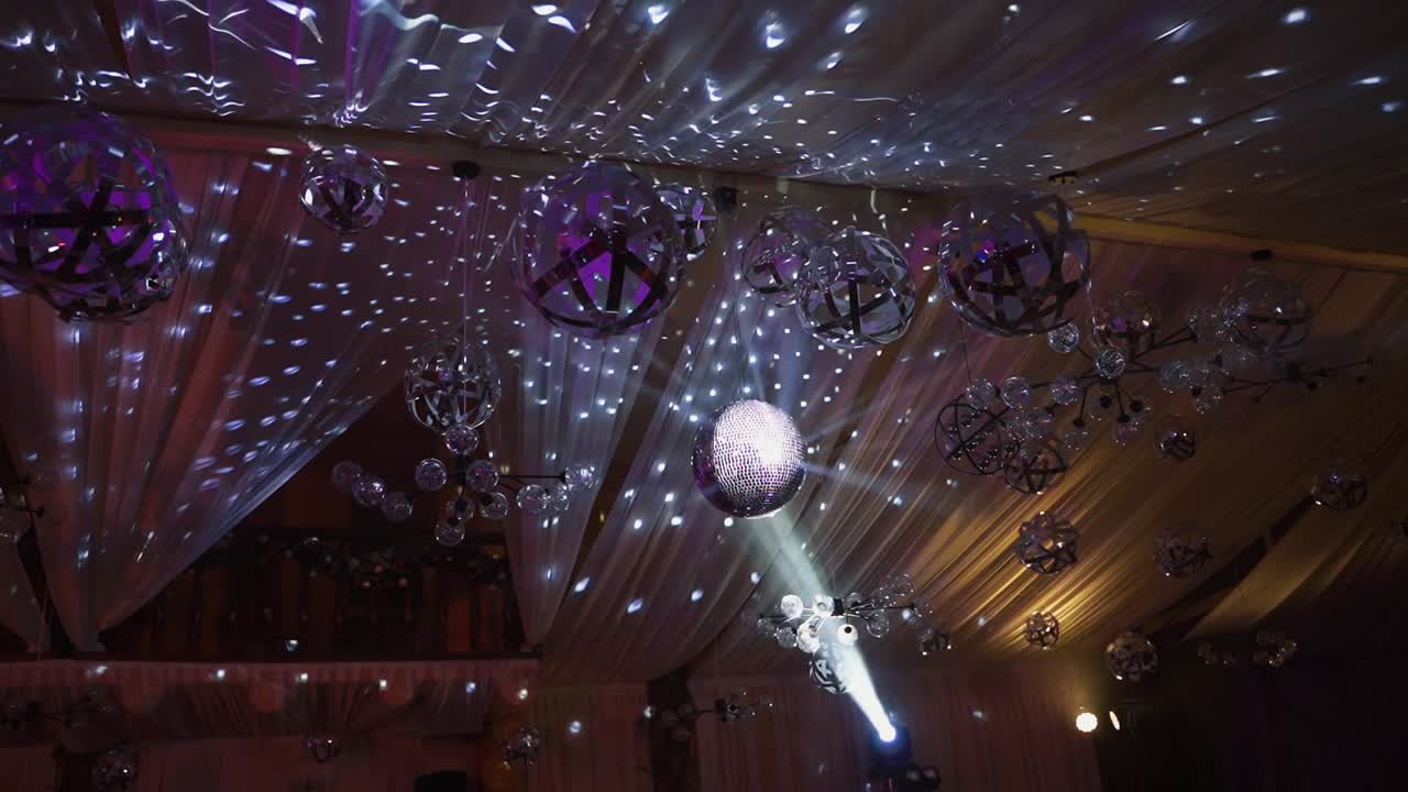 Shining sphere of a night club. Many balls hanging on a shining ceiling at a party. Disco ball spinning and reflecting silver lights.