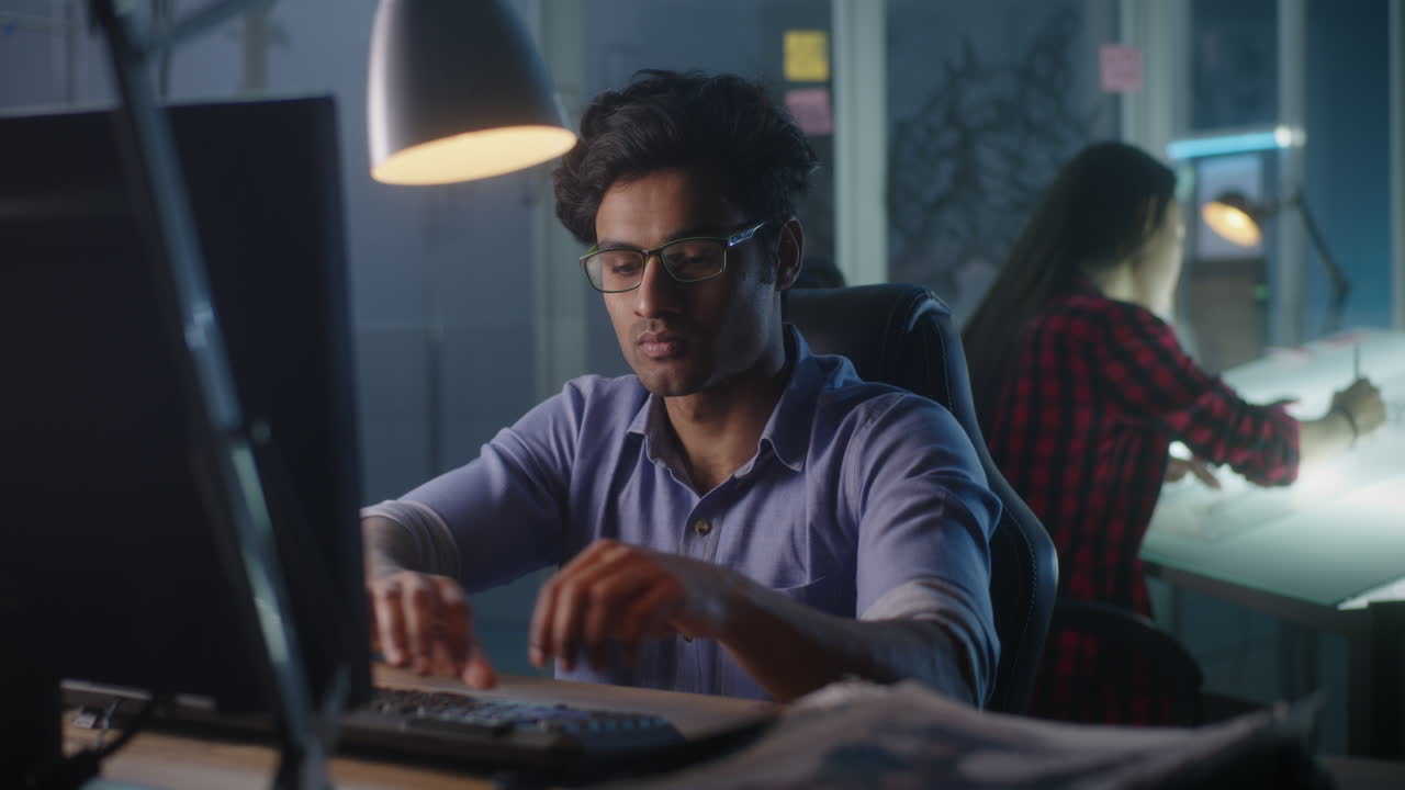 Man working on a computer at night in a design office