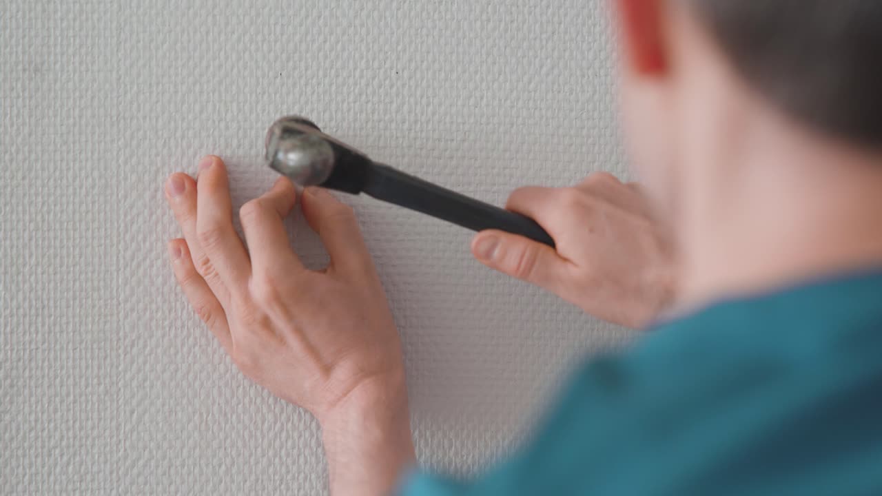 hombre instalando un gancho para colgar cuadros en la pared