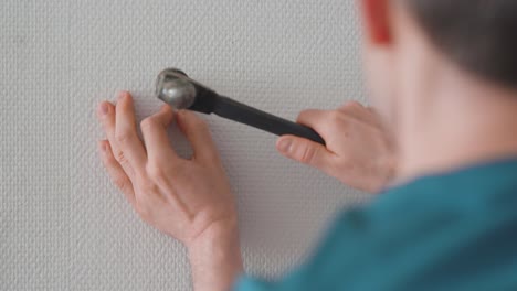 man installing a picture hanging hook on the wall