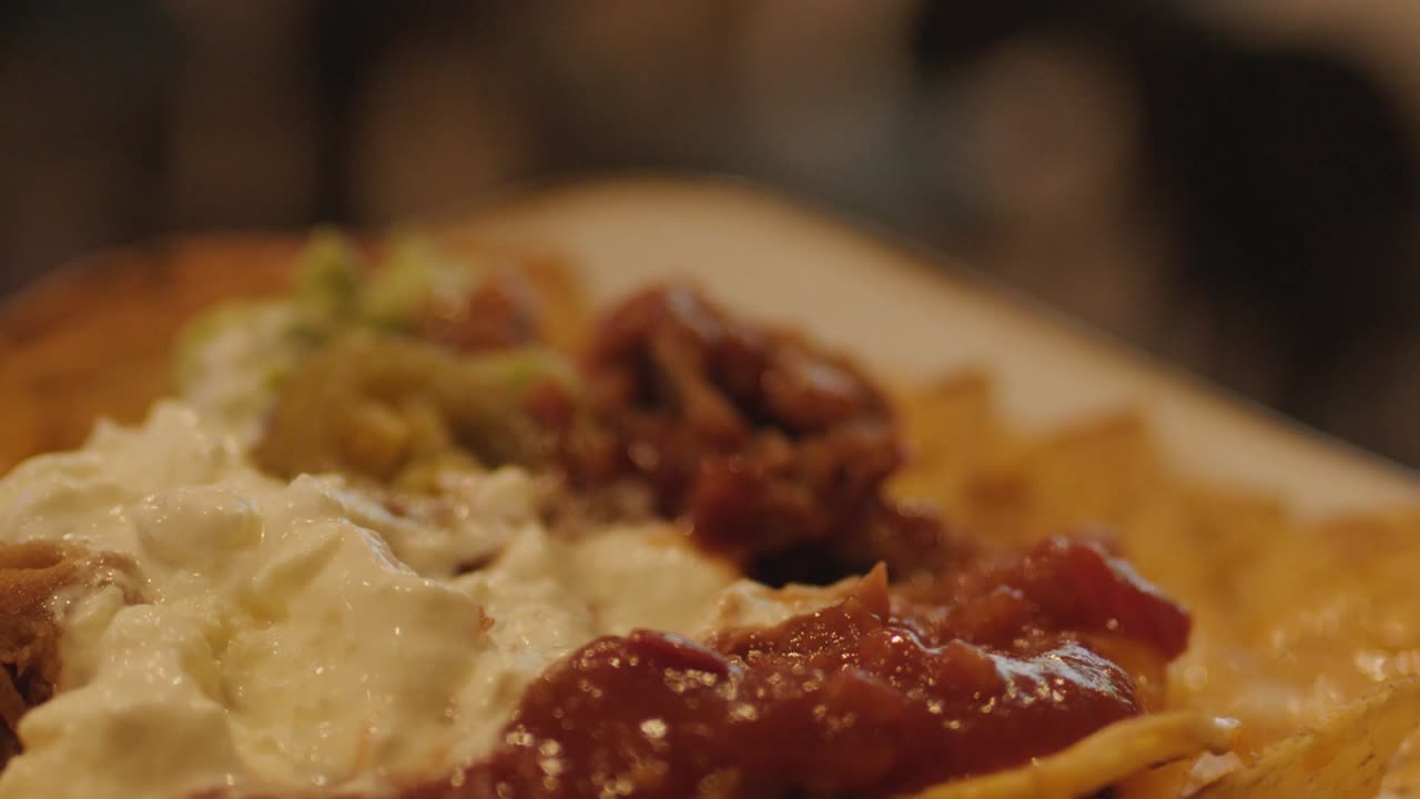 Primissimo piano di una mano che solleva una tortilla con formaggio da un piatto di antipasti