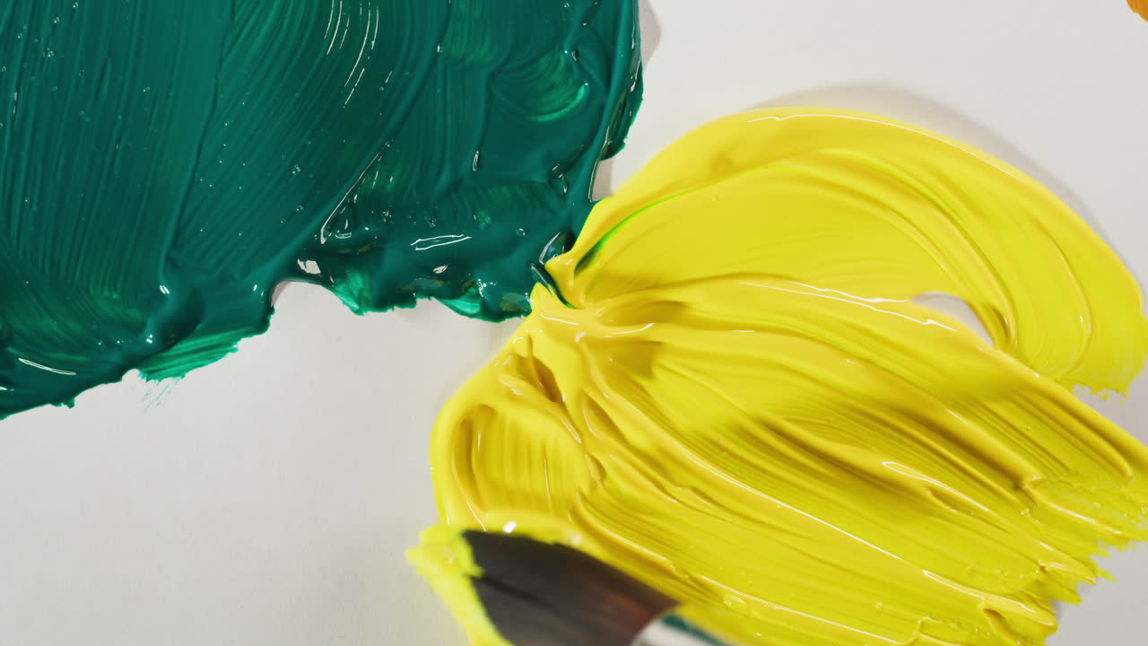 Pincel misturando tinta acrílica amarela e verde