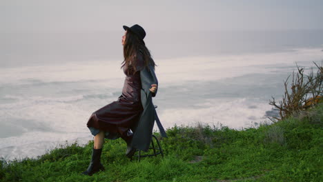 woman sitting chair seashore in front ocean waves evening time. model posing