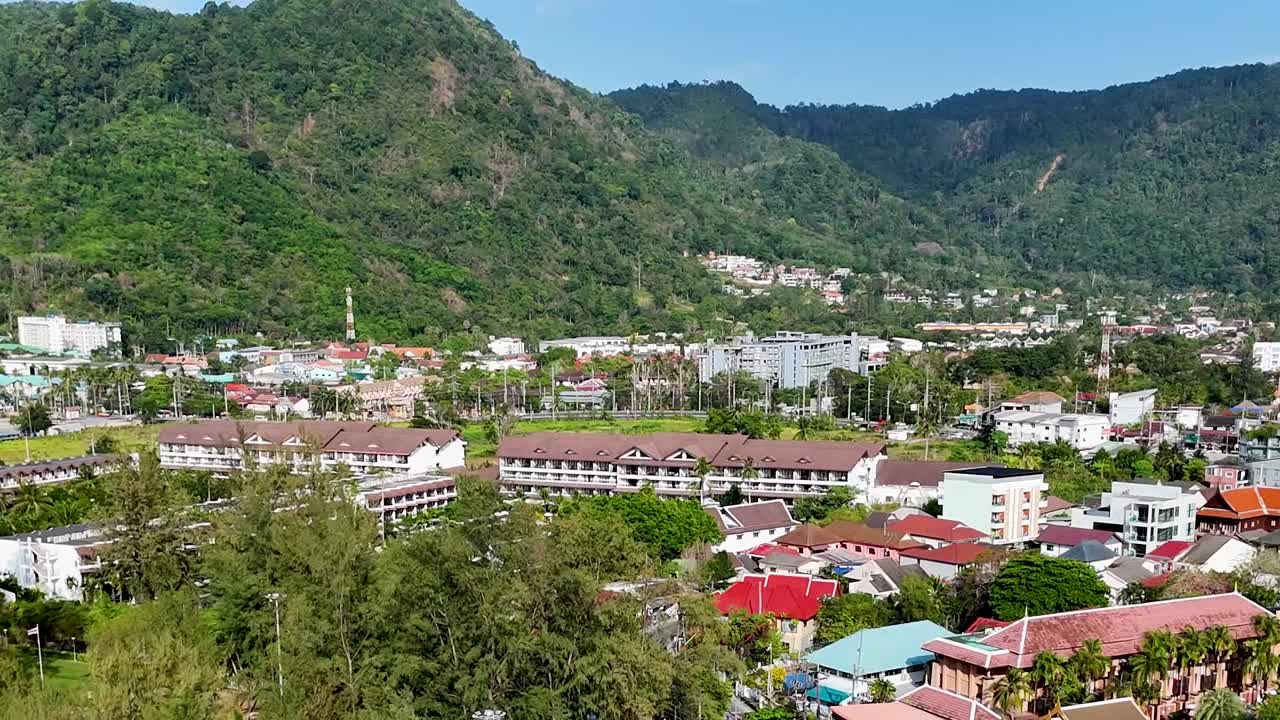 Foto em ângulo alto de uma cidade tropical com edifícios coloridos e colinas verdejantes e densas