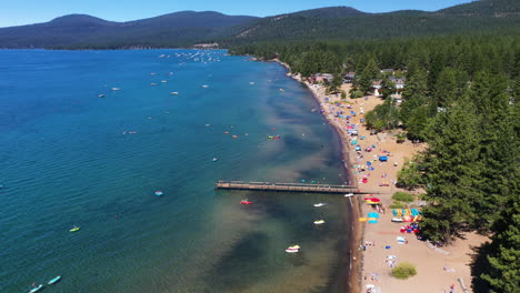 vista aérea del paisaje de personas relajándose en una playa de arena rodeada por un bosque de pinos en el lago tahoe