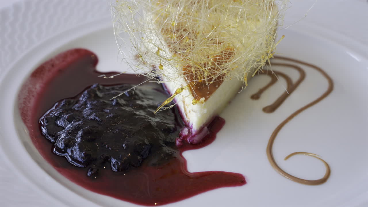 Close up of a piece of cheesecake with blueberry sauce on a white plate