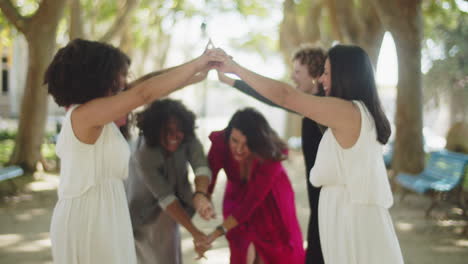 Happy brides playing thread-needle with their guests at the park and then kissing