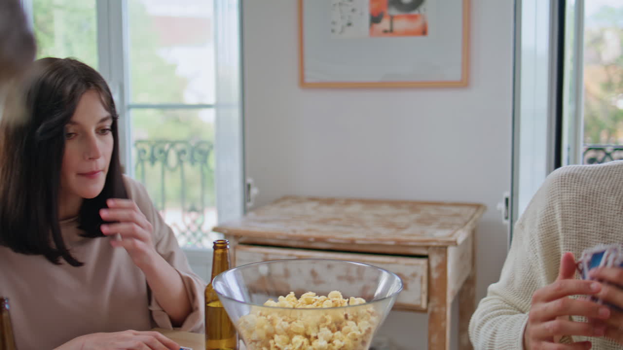 Company friends spend time together on table kitchen playing card game closeup