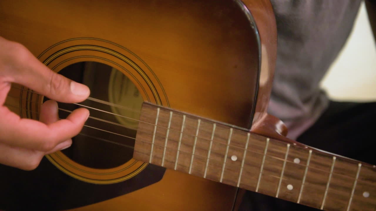 primer plano de una persona tocando una guitarra acústica