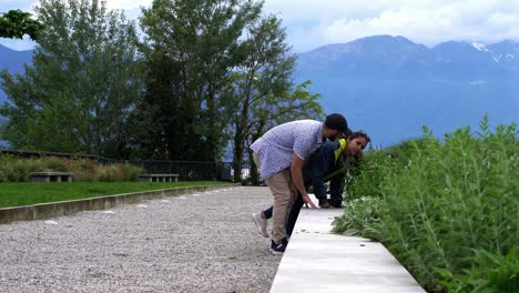 Pareja-De-Viajeros-Huele-Follaje-En-El-Parque-Con-Fondo-De-Montaña