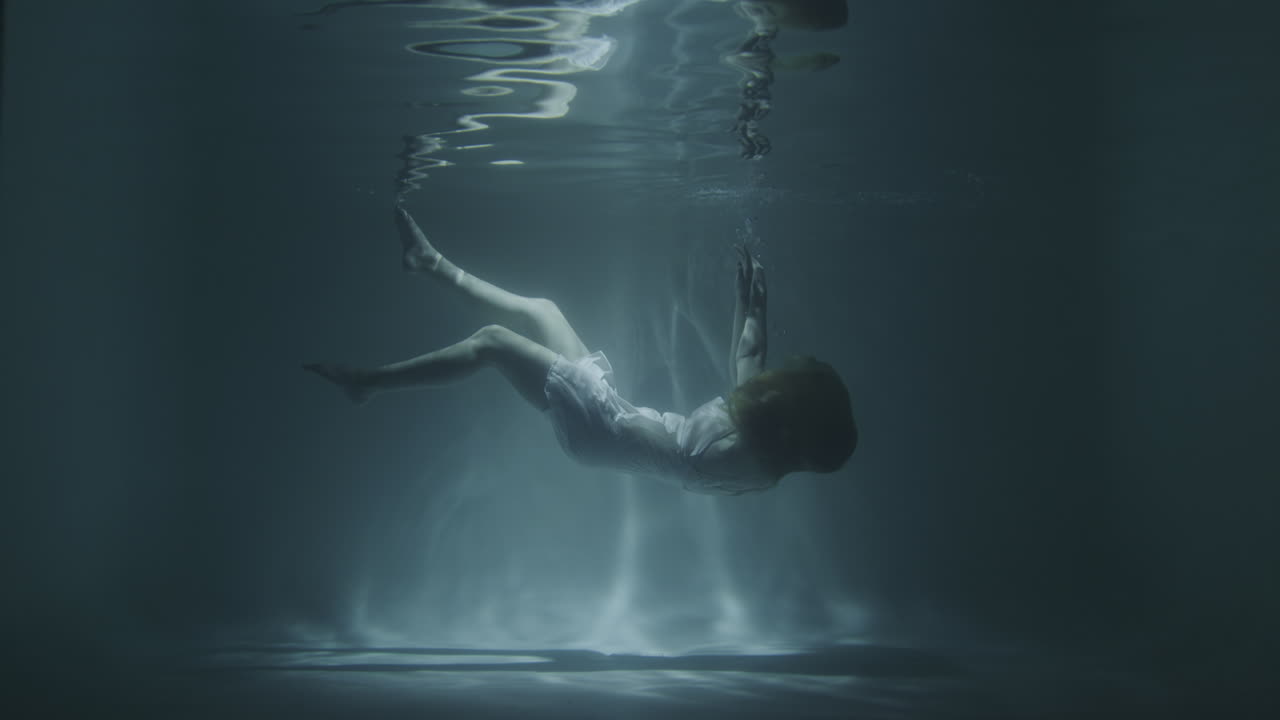 드레스를 입은 아름다운 소녀가 바닥으로 가라앉습니다.