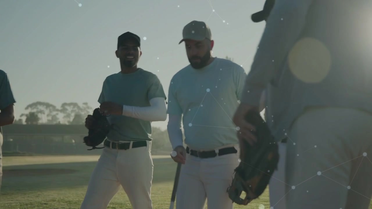 Squadra di baseball che si avvicina alla telecamera, con l'allenatore che indica e inizia un capannello per il riscaldamento, con un leggero flare dell'obiettivo