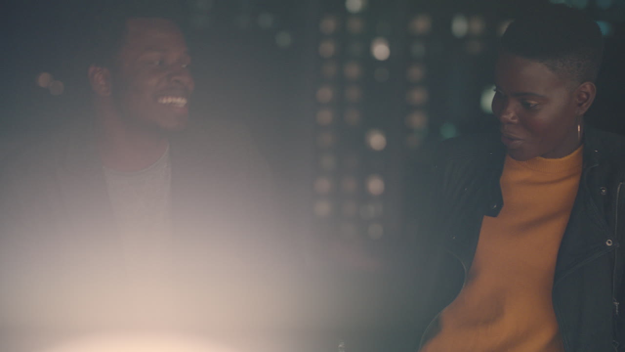 young friends hanging out on rooftop at night chatting having conversation enjoying urban evening african american man flirting with beautiful woman on date