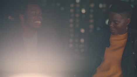 young friends hanging out on rooftop at night chatting having conversation enjoying urban evening african american man flirting with beautiful woman on date