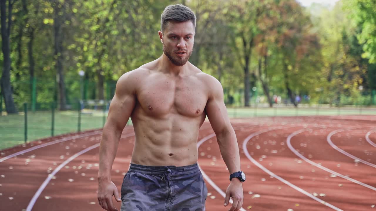 Young sportsman on stadium outside. Professional shirtless sportsman preparing for training session