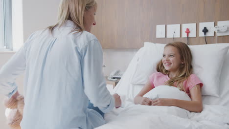 mother visiting daughter lying in bed in hospital ward