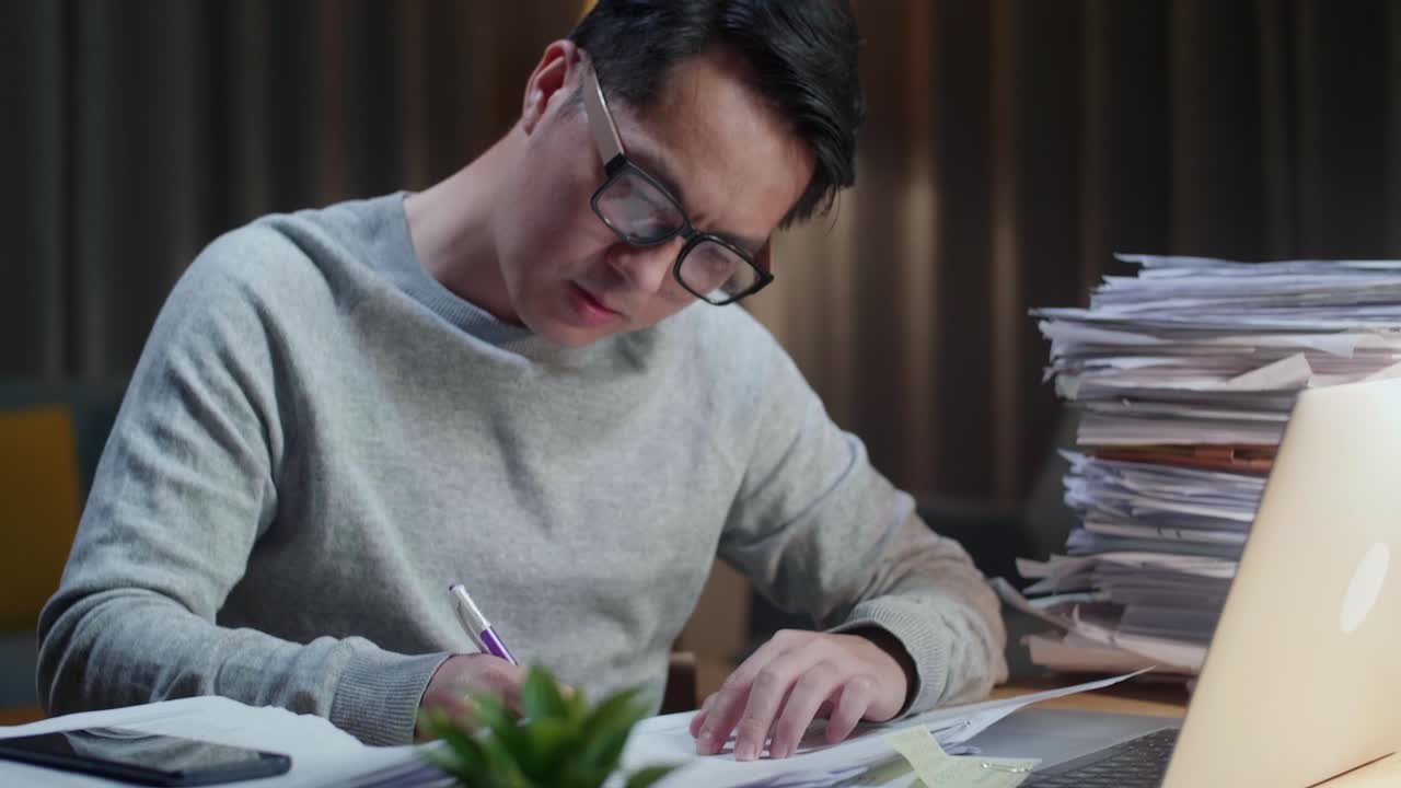 집 에서 문서 를 작업 하는 동안 노트북 을 보고 메모 를 하는 아시아인 의 근접 사진