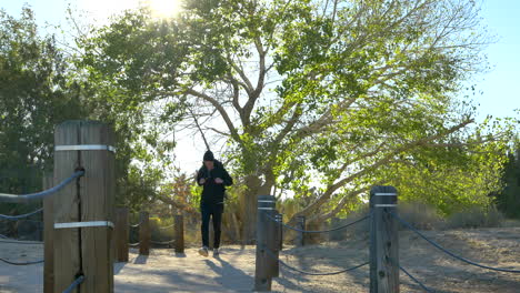 a young fit male hiker with a black backpack hiking alone on a cold morning through a peaceful desert nature preserve in california