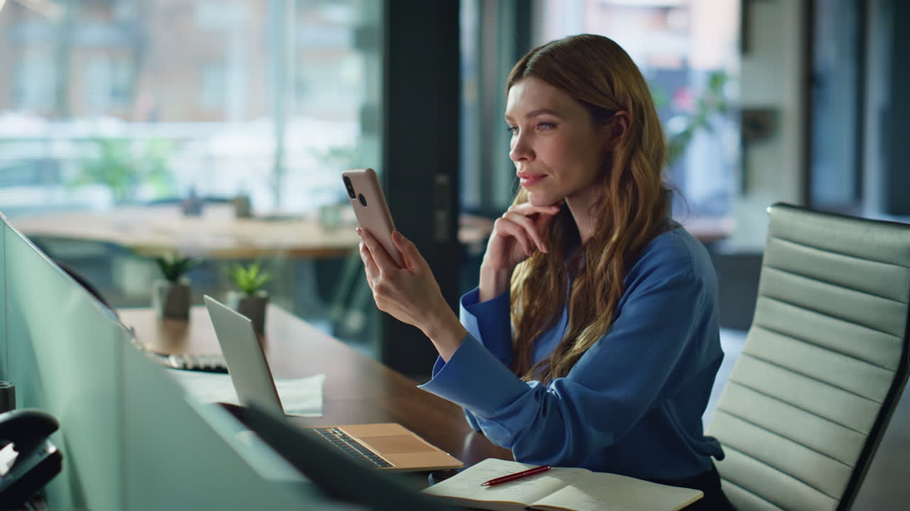 Serious executive looking cellphone screen sitting modern workplace closeup