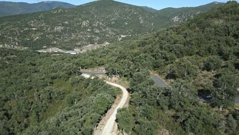 drone follows white car driving through pyrenees green summer mountains, aerial view