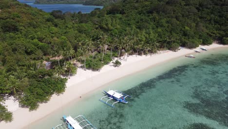 Tour-boats-in-clear-water-of-tropical-sandy-coco-beach,-Coron