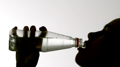 silhouette of woman drinking from bottle