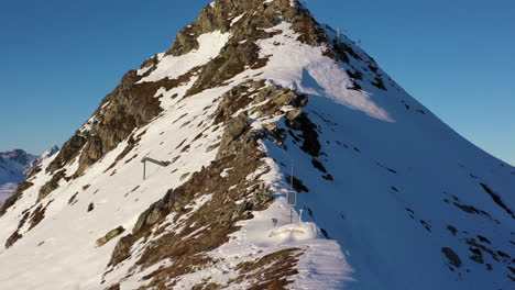disparo de drones, volando por una cresta montañosa cubierta de nieve hasta el pico superior que luego revela un paisaje montañoso que incluye el mont blanc, en la plagne francia