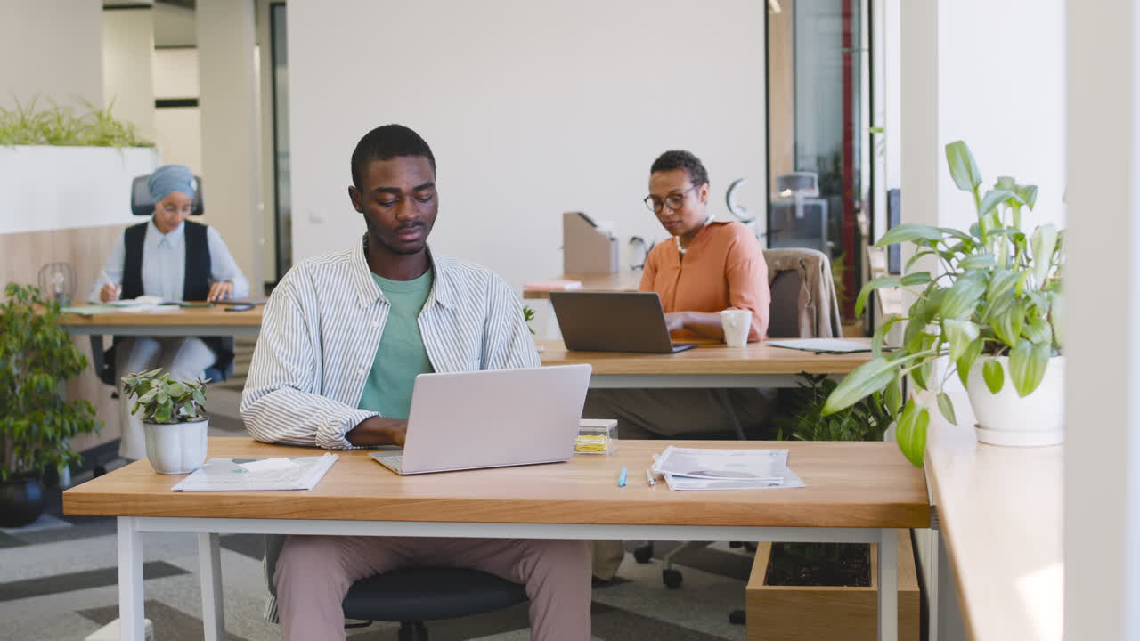 Young Worker Working With Laptop Sitting At His Desk 3