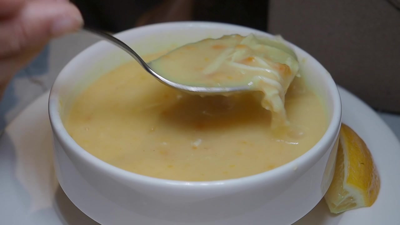 Person Stirring and Eating Creamy Soup in a Bowl