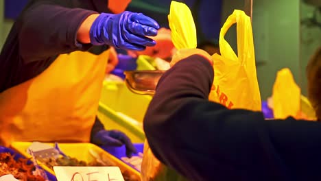 Salesman-Selling-Fish-For-Old-Lady-In-Fish-Market,-Barbate-Port,-Cadiz,-Spain