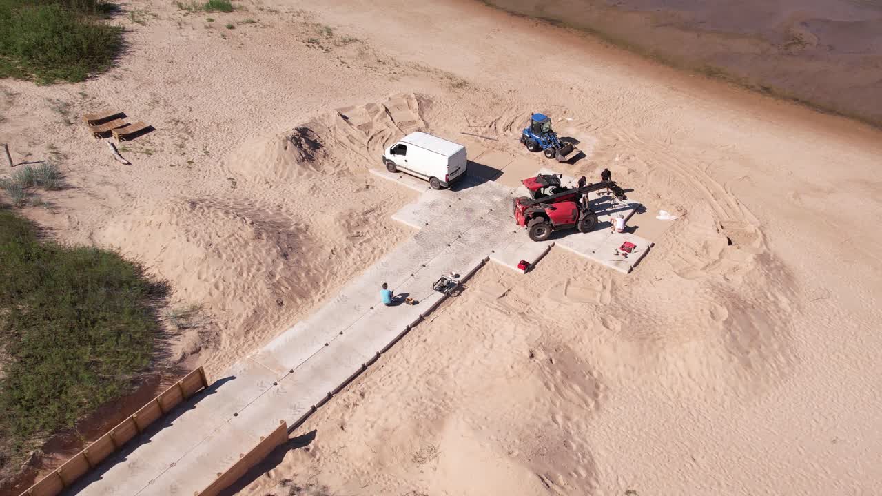 vista aérea de las obras de reparación a lo largo de la costa del mar báltico, con maquinaria de construcción visible y una pasarela de hormigón