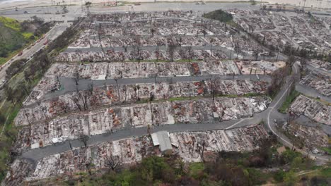 aerial tilting up shot flying over a beachfront mobile home community burned by the palisades fire in los angeles, california. 4k