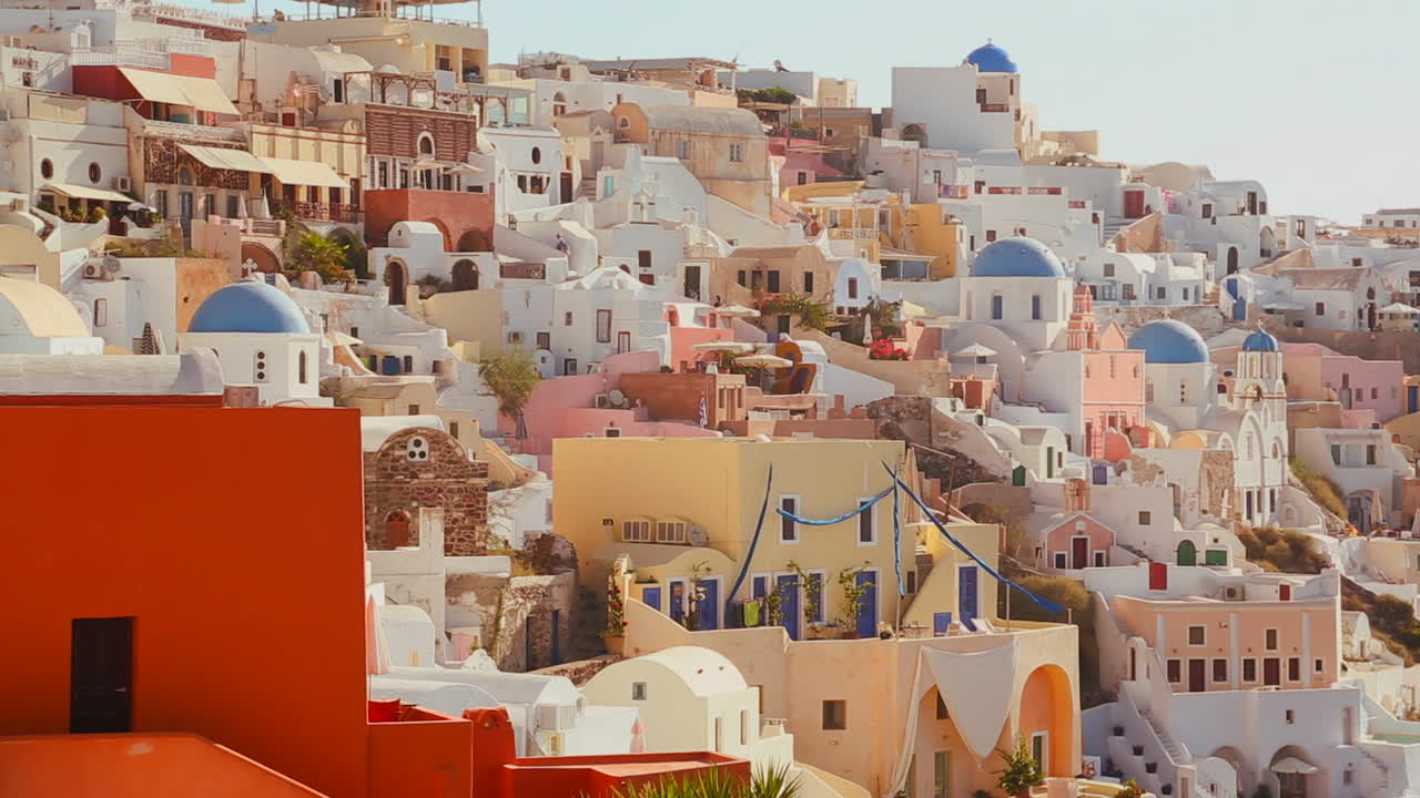 casas multicolores bordean las laderas de la isla griega de santorini con una bandera griega en la distancia 2