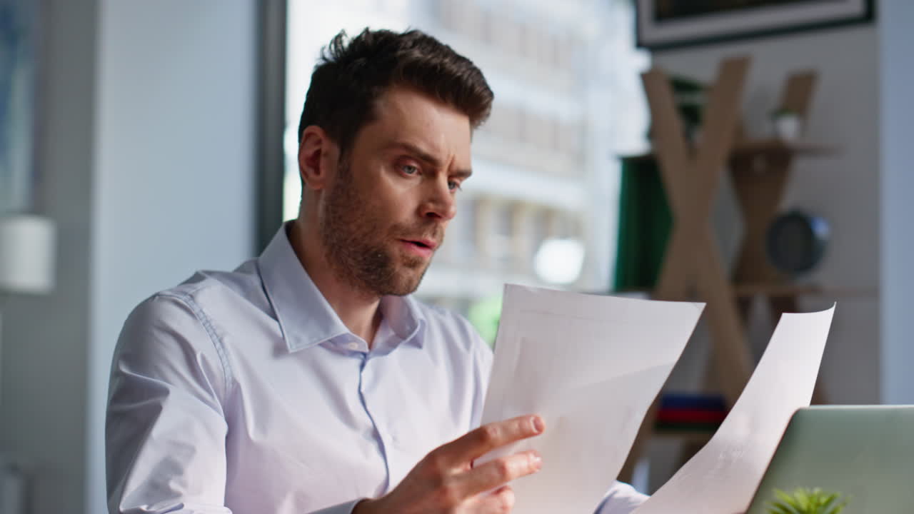 Worried employee reading documents at workspace closeup. Manager dissatisfied