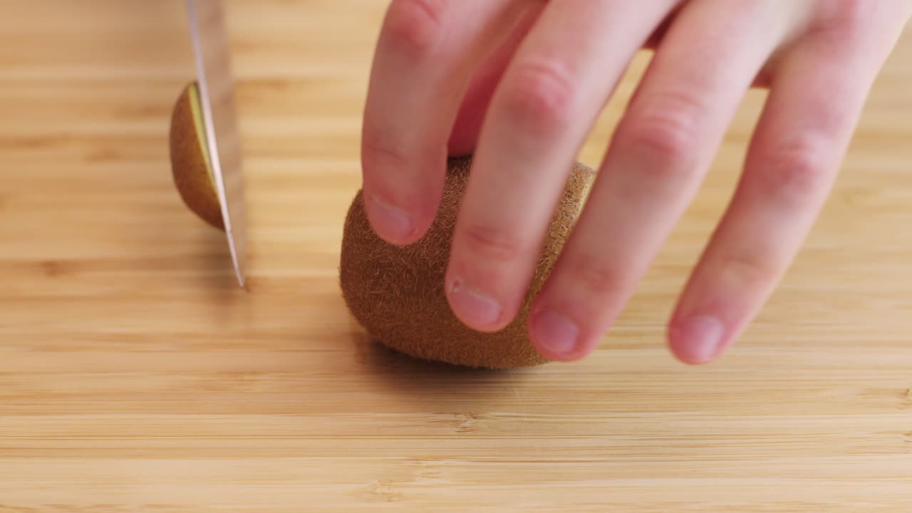 primer plano de un kiwi cortado con un cuchillo y pelado con una cuchara