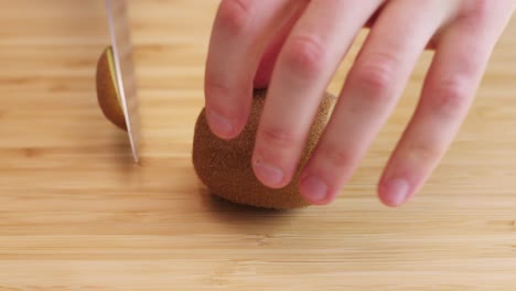 primer plano de un kiwi cortado con un cuchillo y pelado con una cuchara