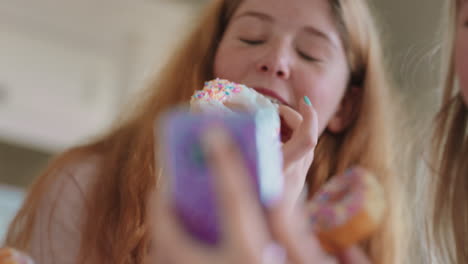 Divertidas-Chicas-Adolescentes-Posando-Con-Donuts-Tomando-Fotos-Usando-Teléfonos-Inteligentes-Para-Compartir-En-Las-Redes-Sociales-Disfrutando-De-Pasar-El-Fin-De-Semana-En-La-Cocina