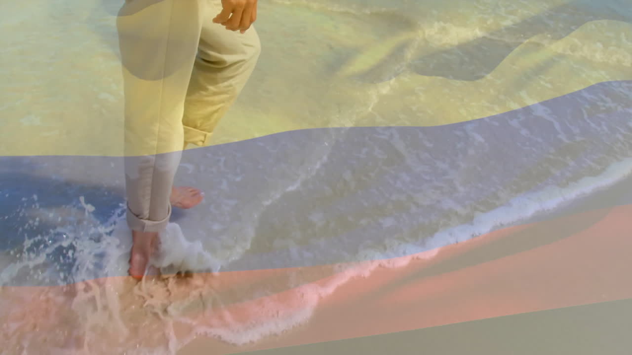animación de la bandera de colombia sobre una mujer biracial caminando en la playa
