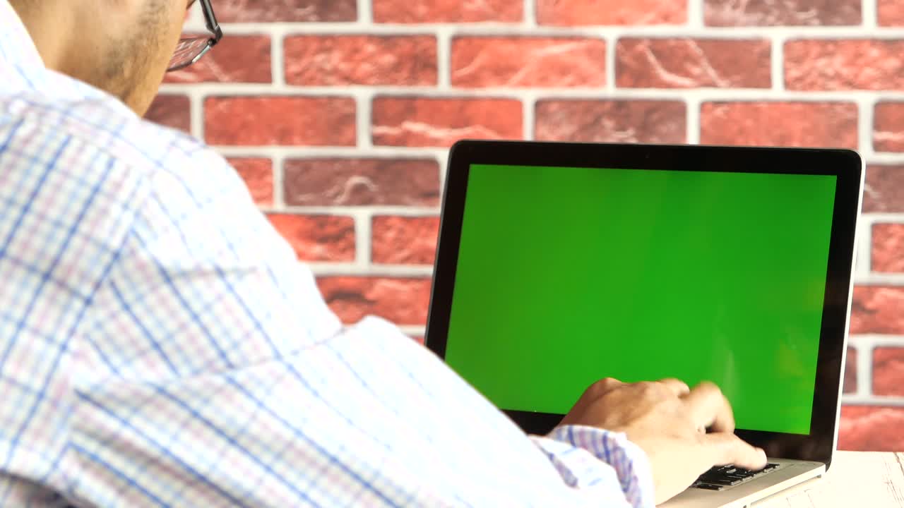 hombre trabajando en una computadora portátil con pantalla verde