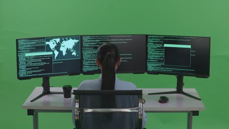 back view of asian woman developer using computer to write code with multiple screens in green screen studio