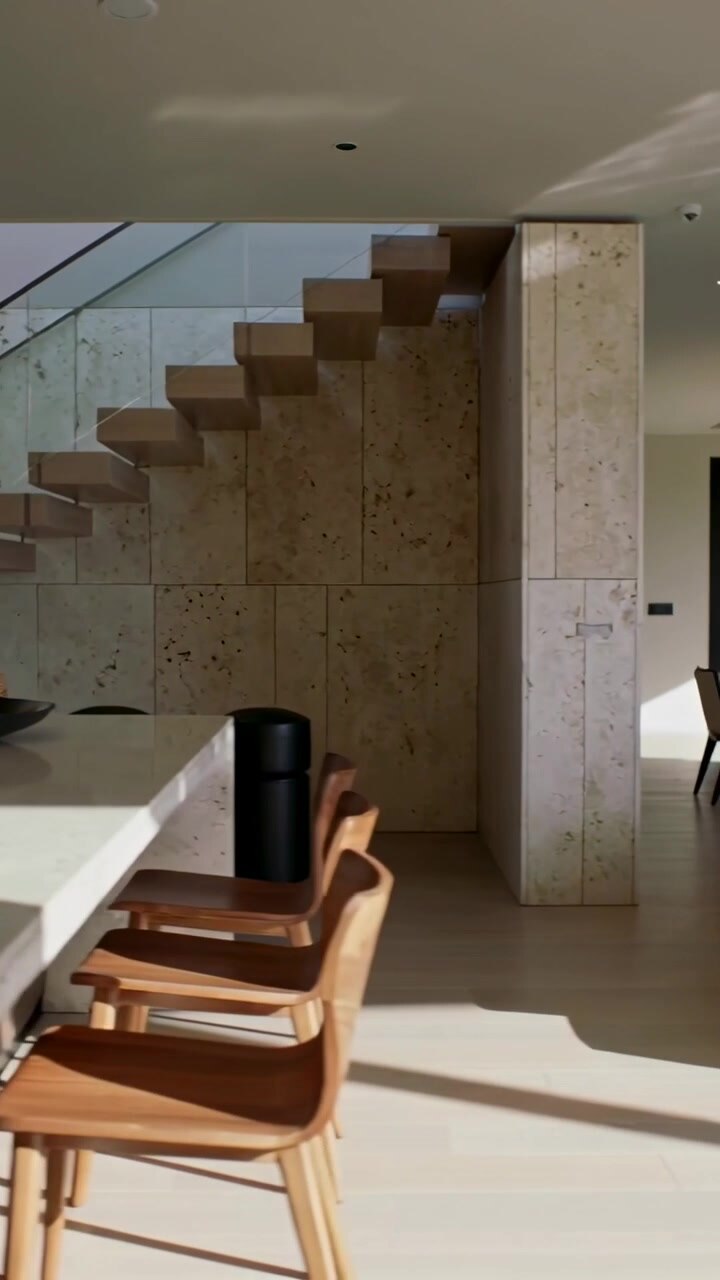 Video verticale: Ripresa con telecamera che si allontana rivelando un'isola in pietra e una scala in una casa moderna illuminata dal sole.