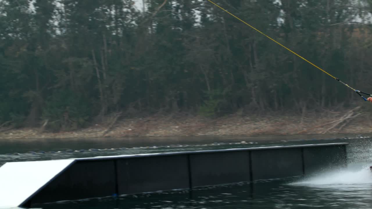 vista frontal de un joven caucásico haciendo trucos en wakeboard en el lago de la ciudad 4k