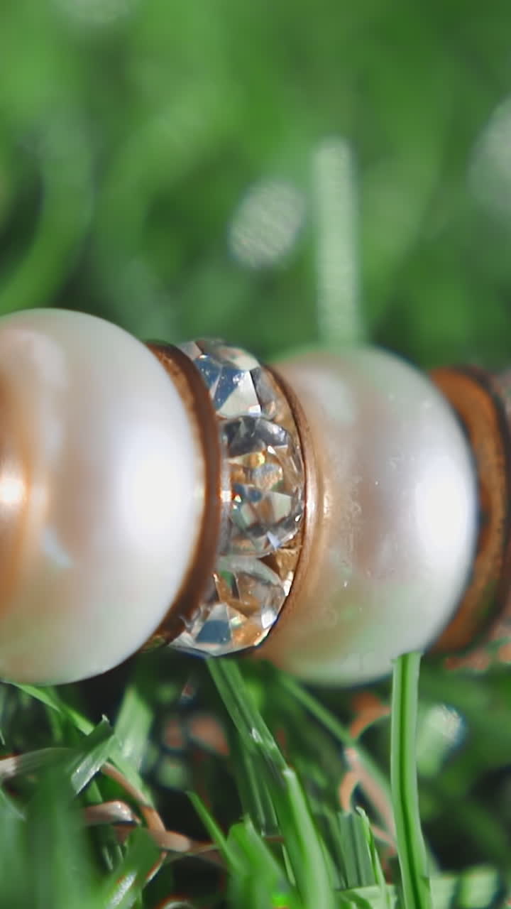 Stylish necklace with pearls and gems on green artificial grass extreme closeup. Jewelry accessory for women. Luxury craft bracelet on lawn