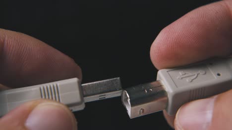 young person shows different usb plugs on black background