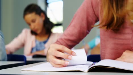 Colegiala-Pasando-Ficha-A-Su-Compañero-De-Clase-Durante-El-Examen-En-El-Aula